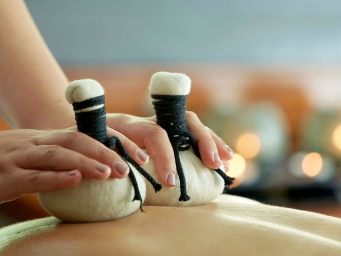 Hands applying herbal treatment on a person's back in a spa at Terra Nostra Garden Hotel one of the Terra Nostra spa