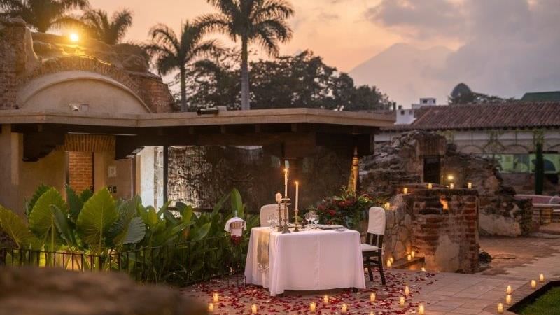 Cena romántica al aire libre en El Refectorio, Casa Santo Domingo, con velas, pétalos de rosa y ruinas históricas