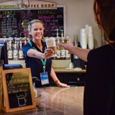 Friendly barista serving a hot cup of coffee in Coffee Shop at Margaritaville Resort Biloxi