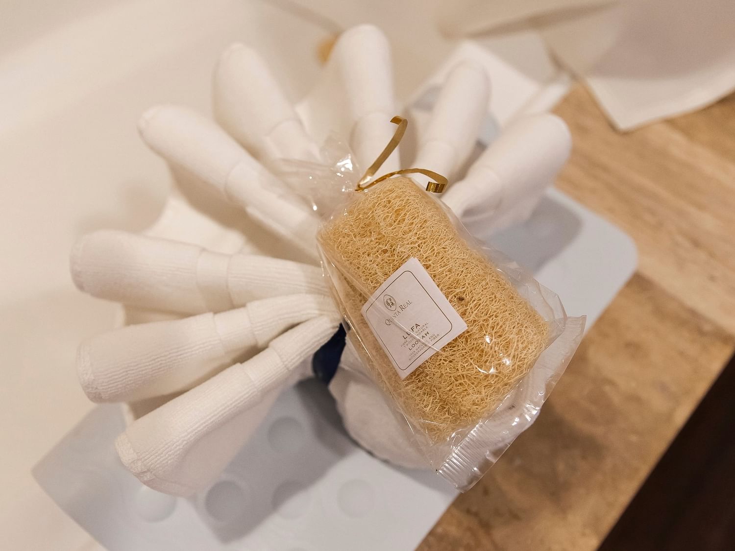 Natural loofah sponge with gold pump dispenser arranged on white towels in the King Presidential Suite at Quinta Real Zacatecas.
