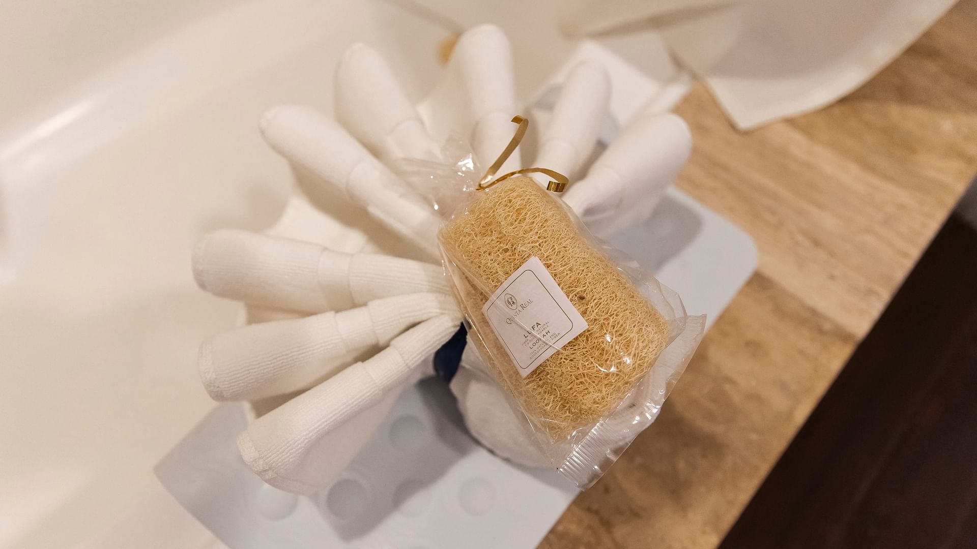 Natural loofah sponge with gold pump dispenser arranged on white towels in the King Presidential Suite at Quinta Real Zacatecas.