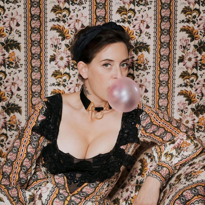 Fashion designer Lena Hoschek poses in a vintage floral setting, wearing a bold and colorful dress at Hotel Motto Vienna