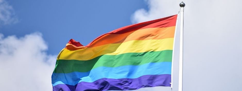 Pride flag fluttering proudly against a bright blue sky, near Novotel Sydney International Airport