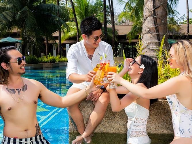 Three people celebrating with drinks by a pool, enjoying at Chatrium Royal Lake Yangon