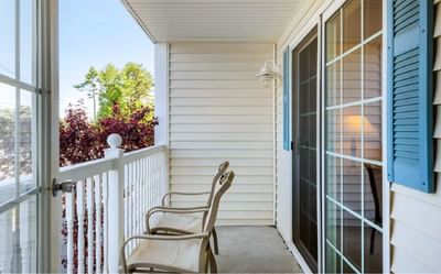 Cozy balcony with two chairs and white railing, overlooking greenery and blue skies at Ogunquit Hotel and Suites