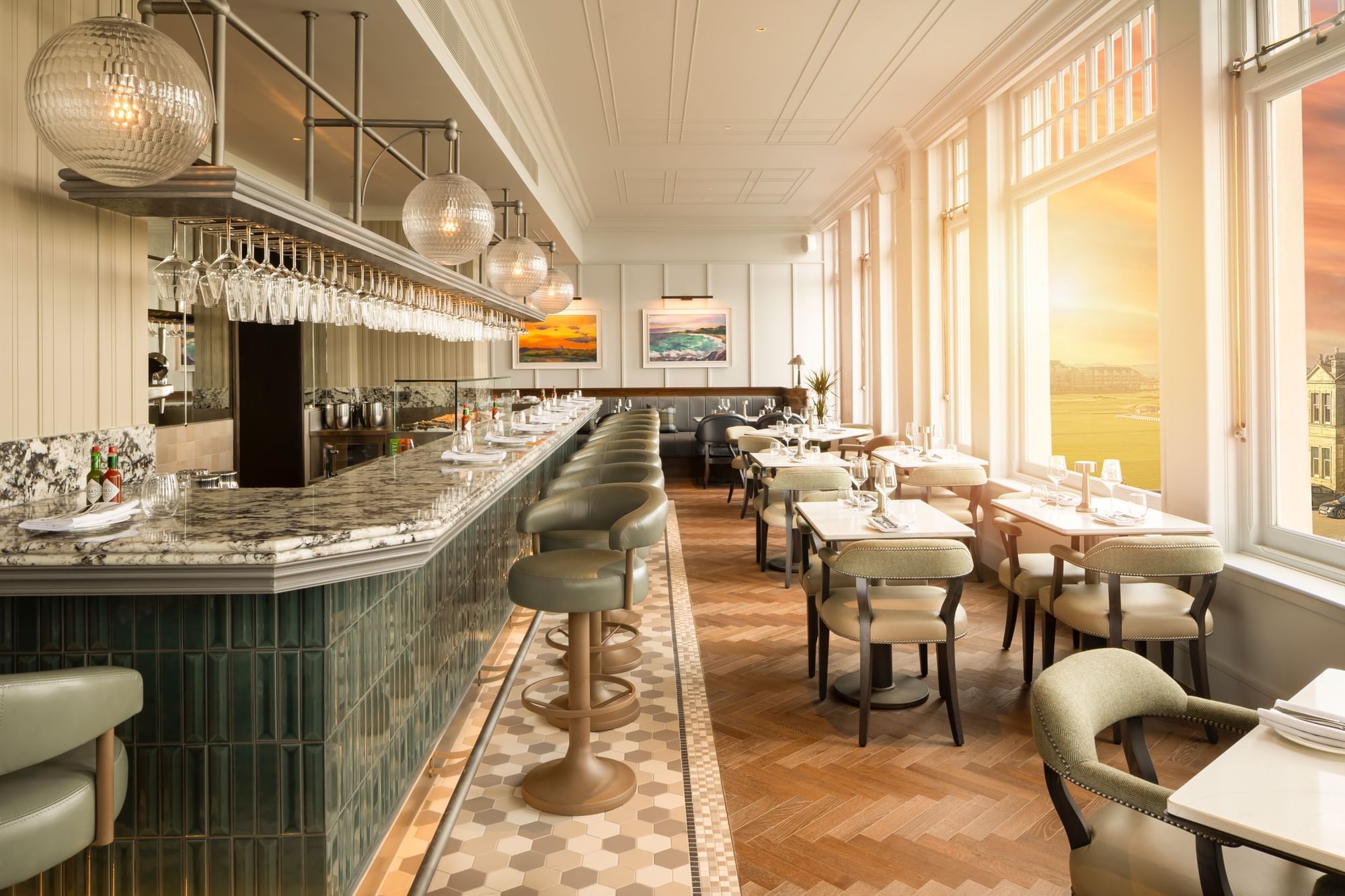 Counter with stools & dining tables by tall windows framing a stunning sunset view at Ondine Oyster & Grill in Seaton House
