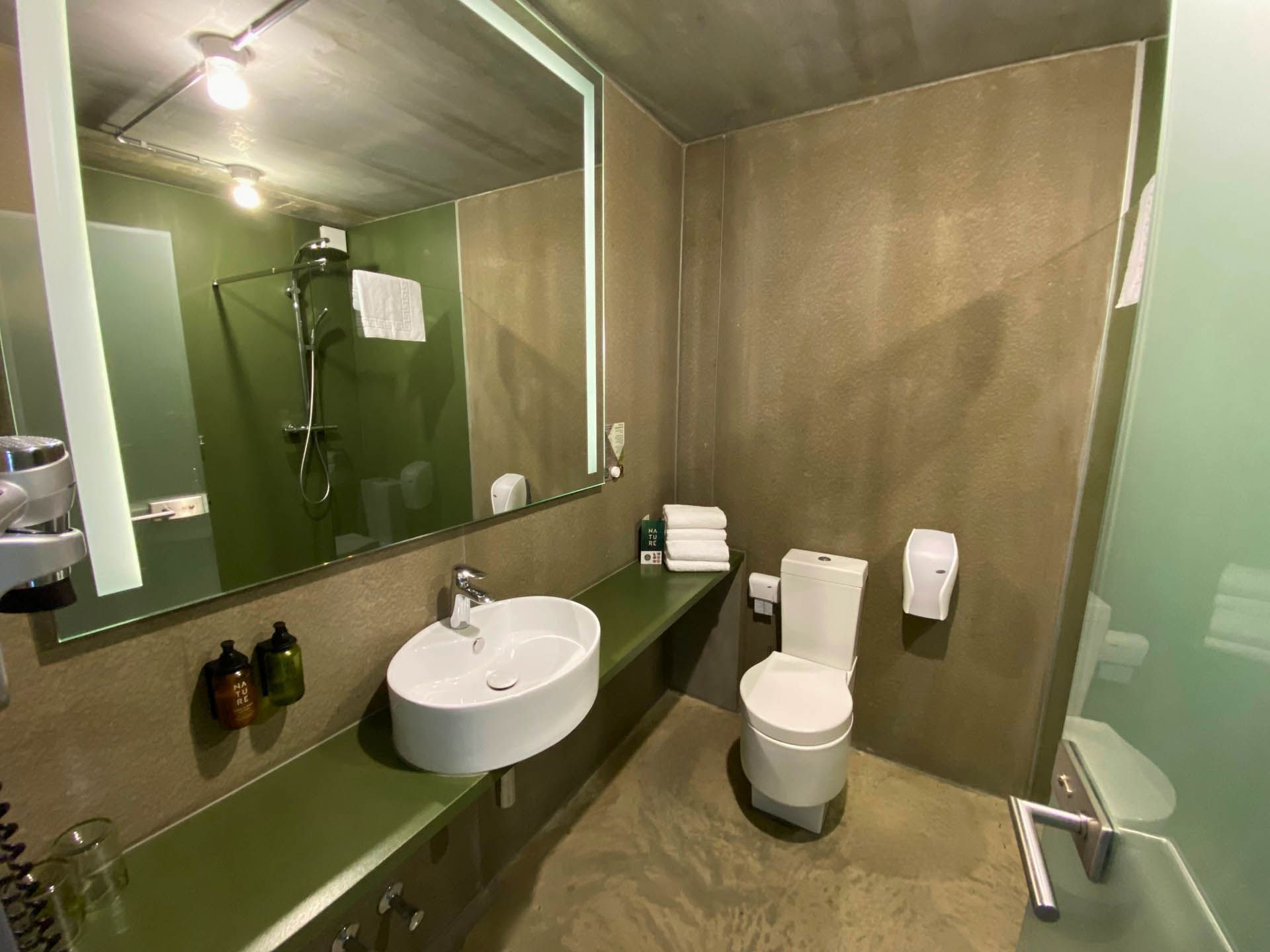 Long Stay Room bathroom featuring a vanity with a large mirror and lavatory at the Avaneo Hotel