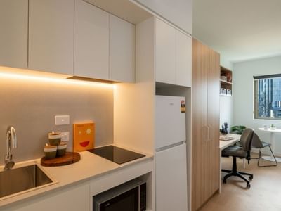 Modern kitchen with sink, fridge, and microwave in a UniLodge Brisbane City unit.
