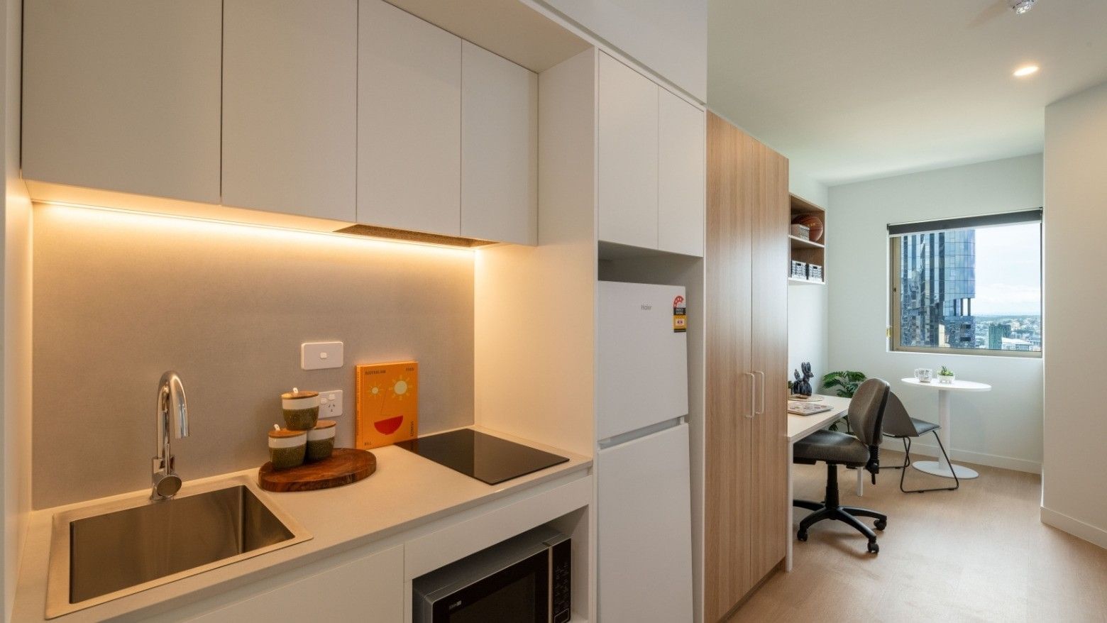 Modern kitchen with sink, fridge, and microwave in a UniLodge Brisbane City unit.