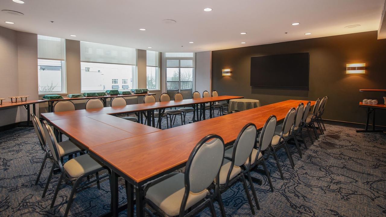 A large conference room with long tables, chairs, and a flat screen TV at Coast Bastion Hotel.