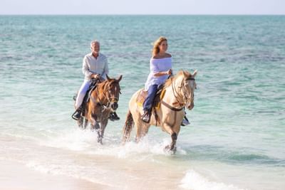 Couple riding horses at the sea near The Somerset on Grace Bay