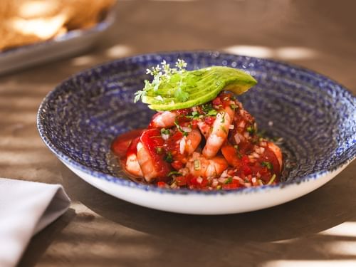 Shrimp dish with avocado garnish in a blue bowl at Tortugas restaurant in Cabo San Lucas at Hacienda Del Mar Los Cabos Redesign.