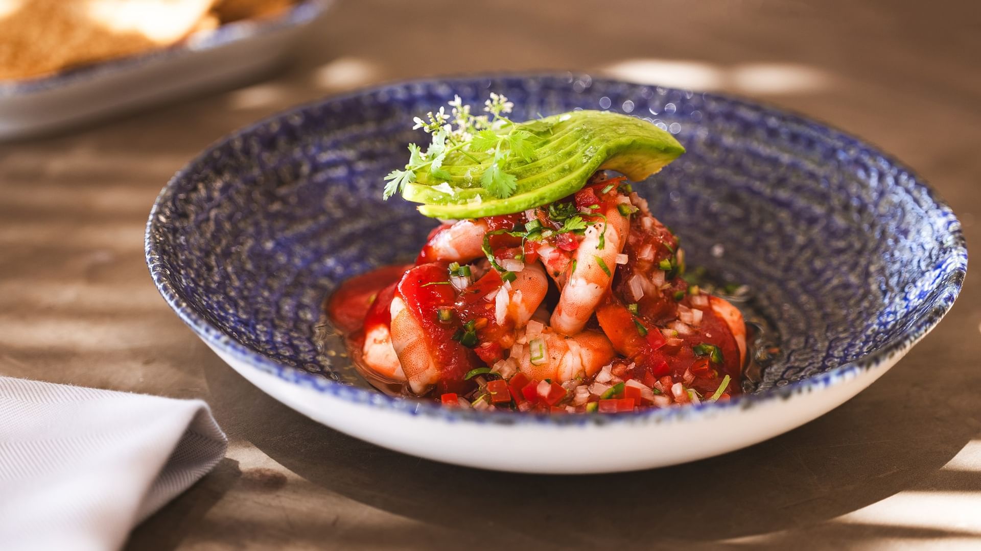 Shrimp dish with avocado garnish in a blue bowl at Tortugas restaurant in Cabo San Lucas at Hacienda Del Mar Los Cabos Redesign.