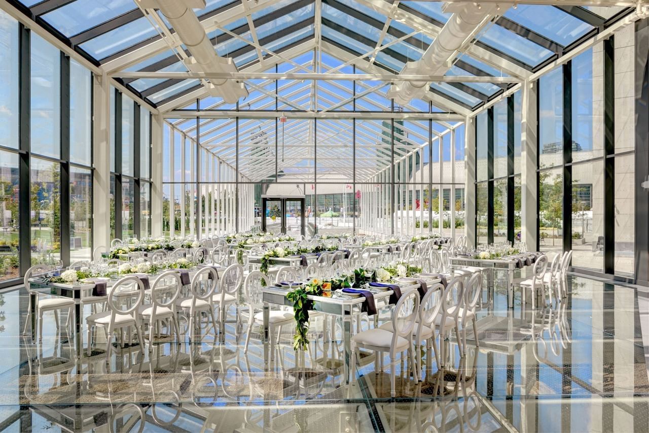 New Fort Hall Day set up with elegant dining tables and white chairs under glass ceiling set at Hotel X Toronto