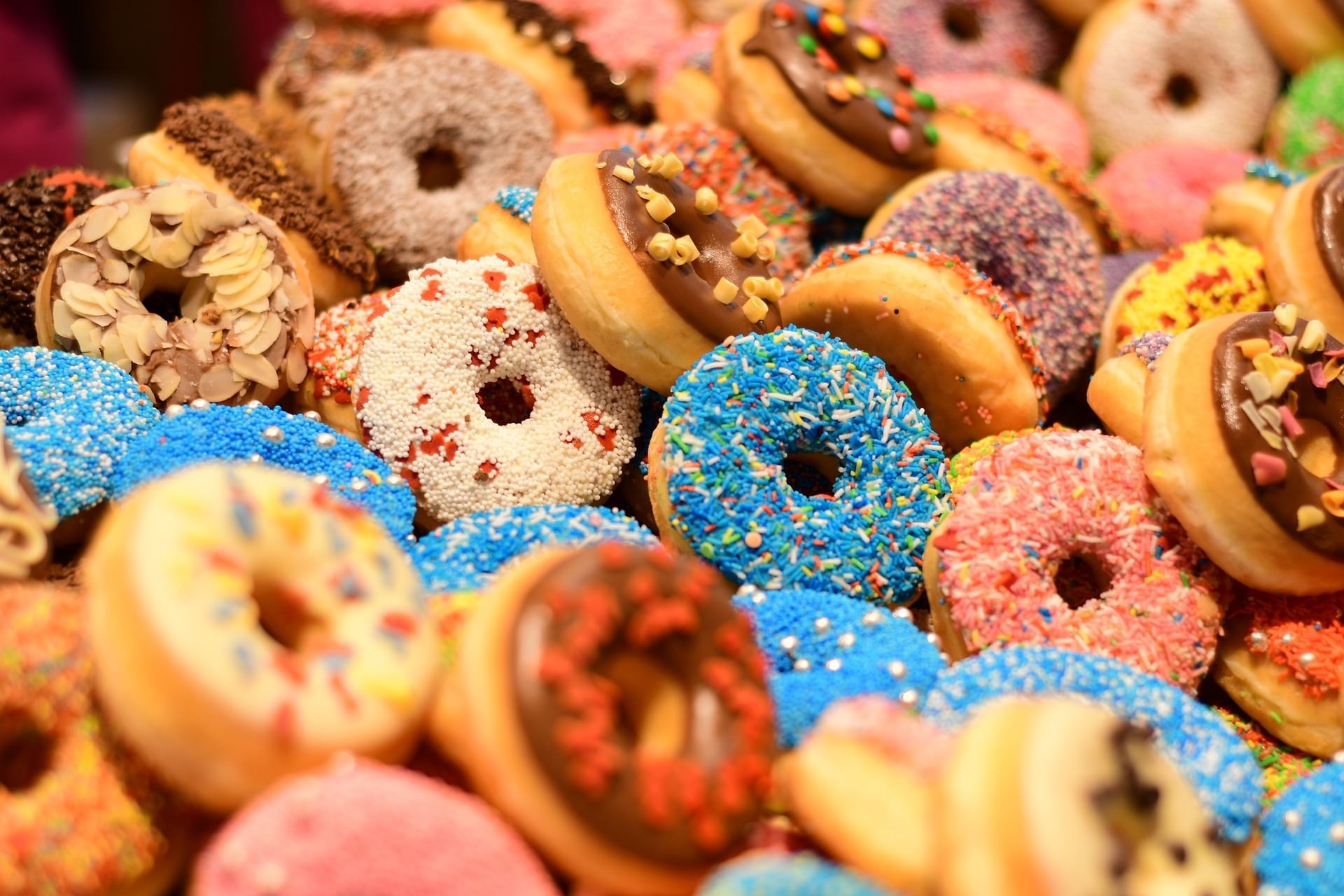 A bunch of donuts with vibrant colored frosting topped with sugary sprinkles.