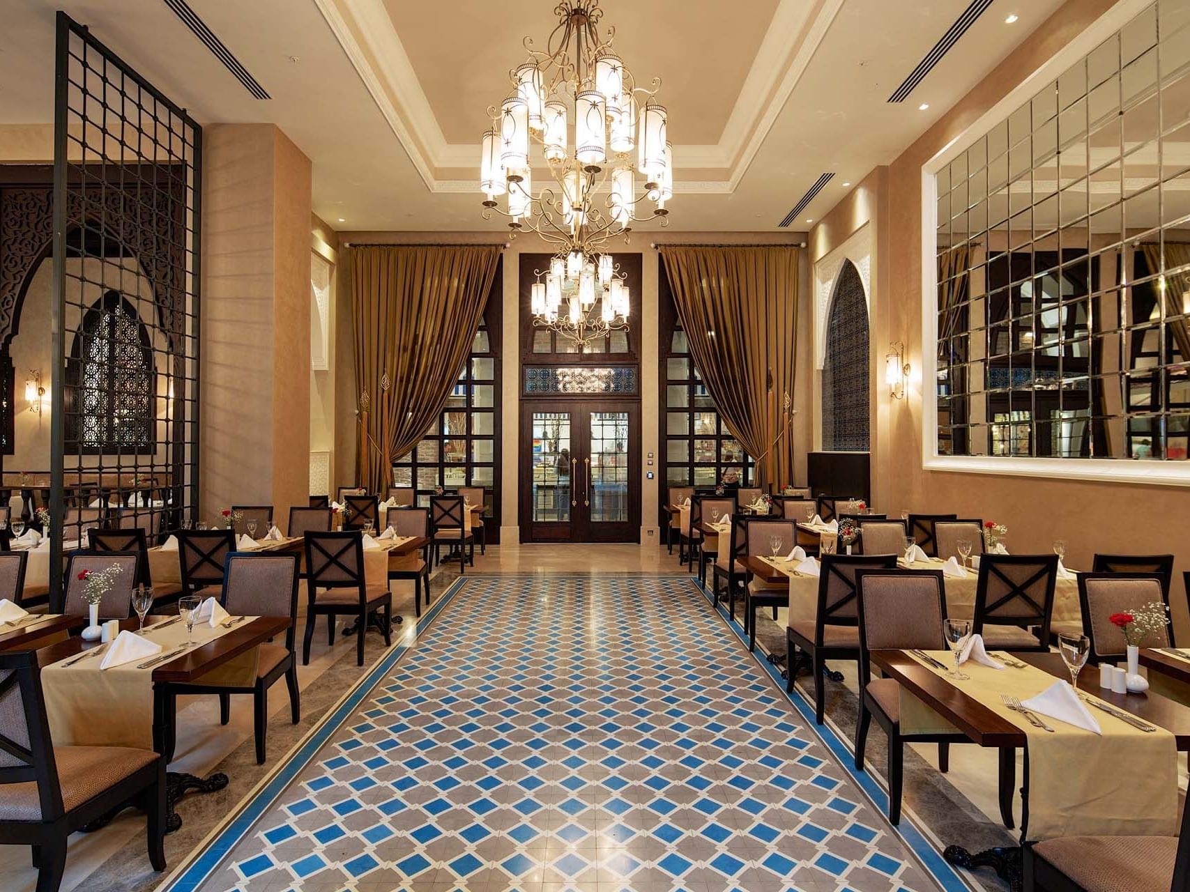 Elegant restaurant interior with ornate chandeliers, tiled floor, and set dining tables at Titanic Deluxe Golf Belek