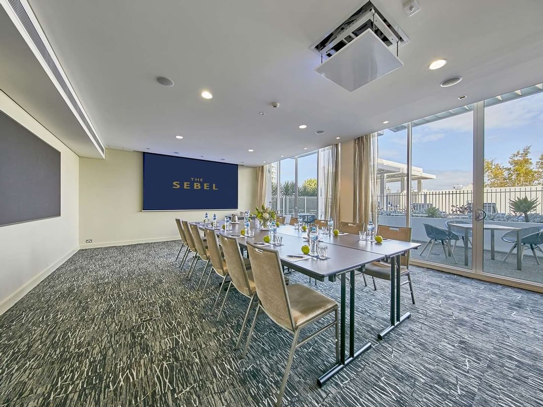 Bright, modern conference room at The Sebel Mandurah with a long table and large windows opening to a patio