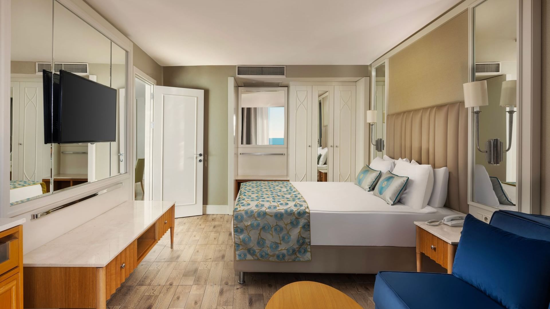 Colonel Suite with a large bed featuring blue floral bedding, a sofa, wooden flooring, and a desk at Titanic Deluxe Lara