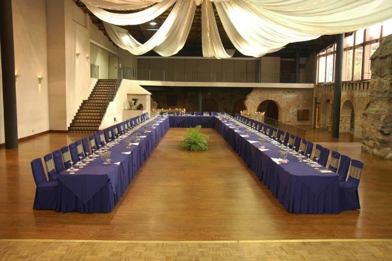 Large ballroom with a U-shaped table arrangement and draping white fabric on the ceiling at Casa Santo Domingo