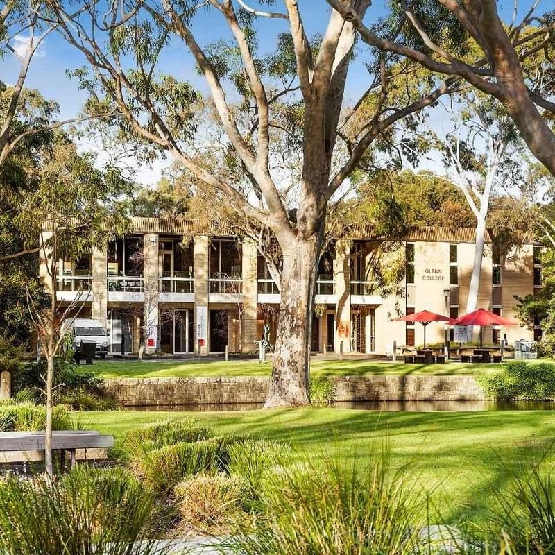 La Trobe University Glenn College building with lush greenery and red umbrellas.