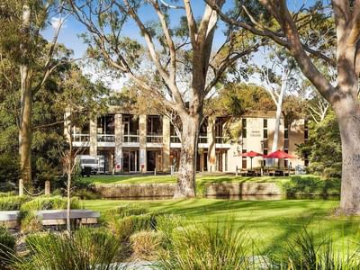 La Trobe University Glenn College building with lush greenery and red umbrellas.