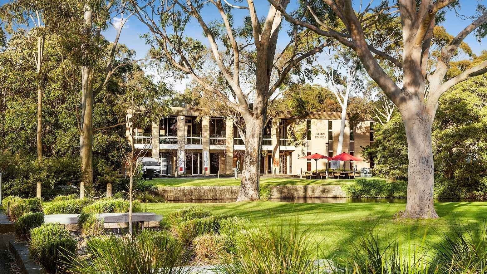 La Trobe University Glenn College building with lush greenery and red umbrellas.