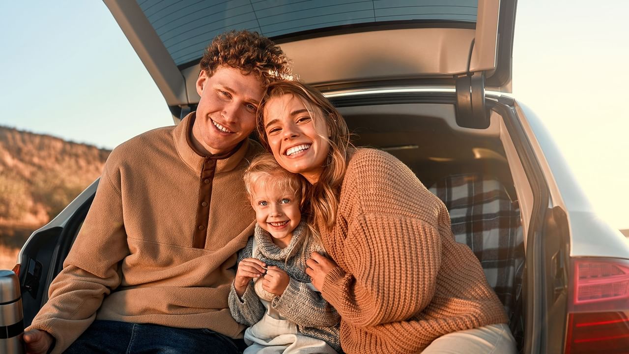 Family sitting together in a car trunk and enjoying a warm sunset near Coast Penticton Hotel