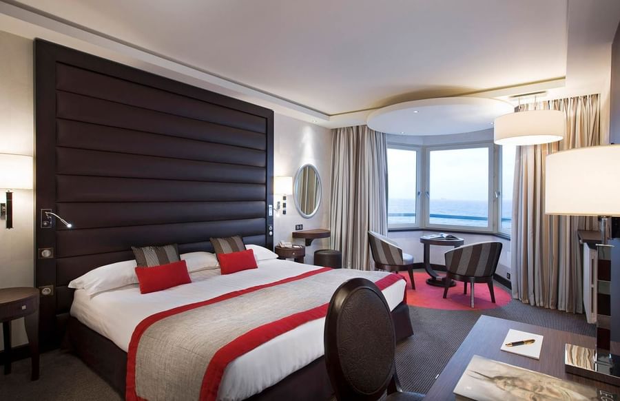 Double bed with cozy seating area with an ocean view in Croisiere Grand Large Room at Le Grand Hôtel des Thermes