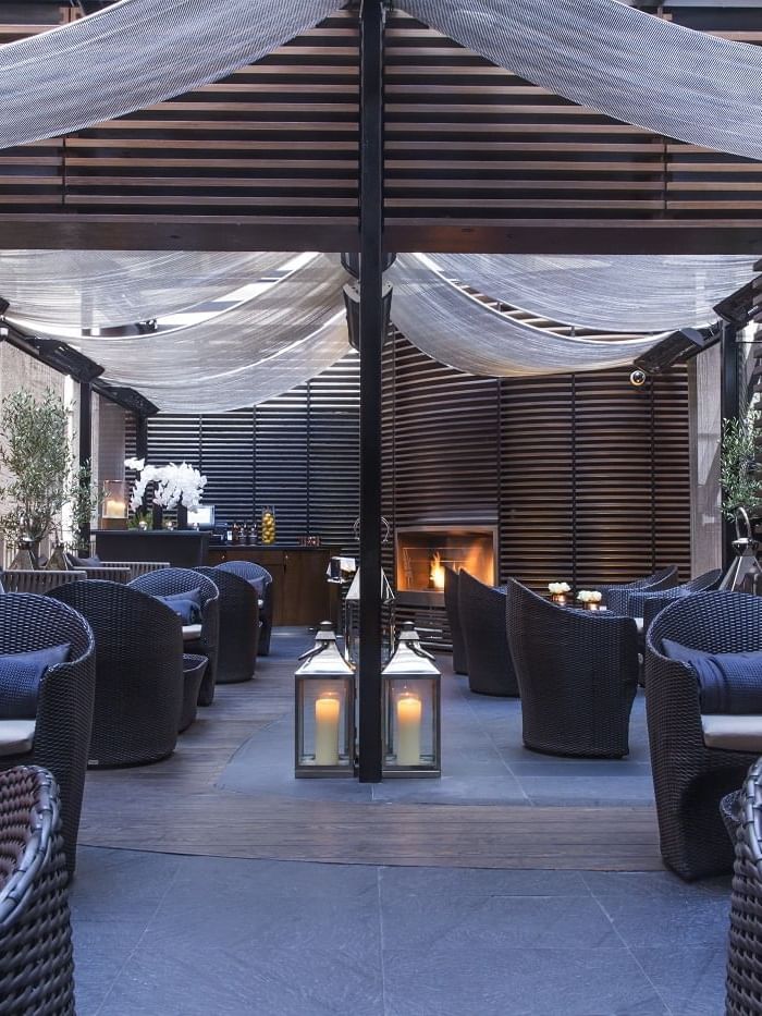 A terrace lounge area with wicker chairs, candles at The May Fair Hotel.
