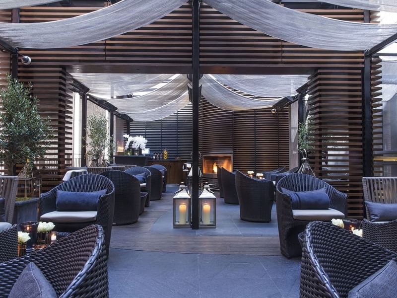 A terrace lounge area with wicker chairs, candles at The May Fair Hotel.