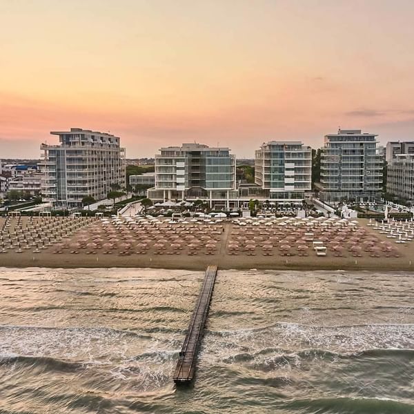 Distant view of Falkensteiner Hotel & Spa Jesolo with beach lounging area with umbrellas