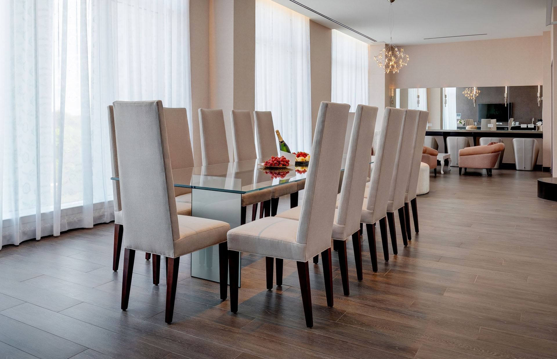 Glass top dining table in The Pearl Room with high chairs set beside floor to ceiling windows at Hotel X Toronto
