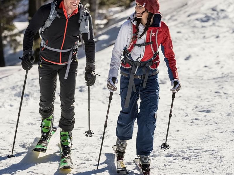 A couple ski touring on a mountain near Falkensteiner Hotels