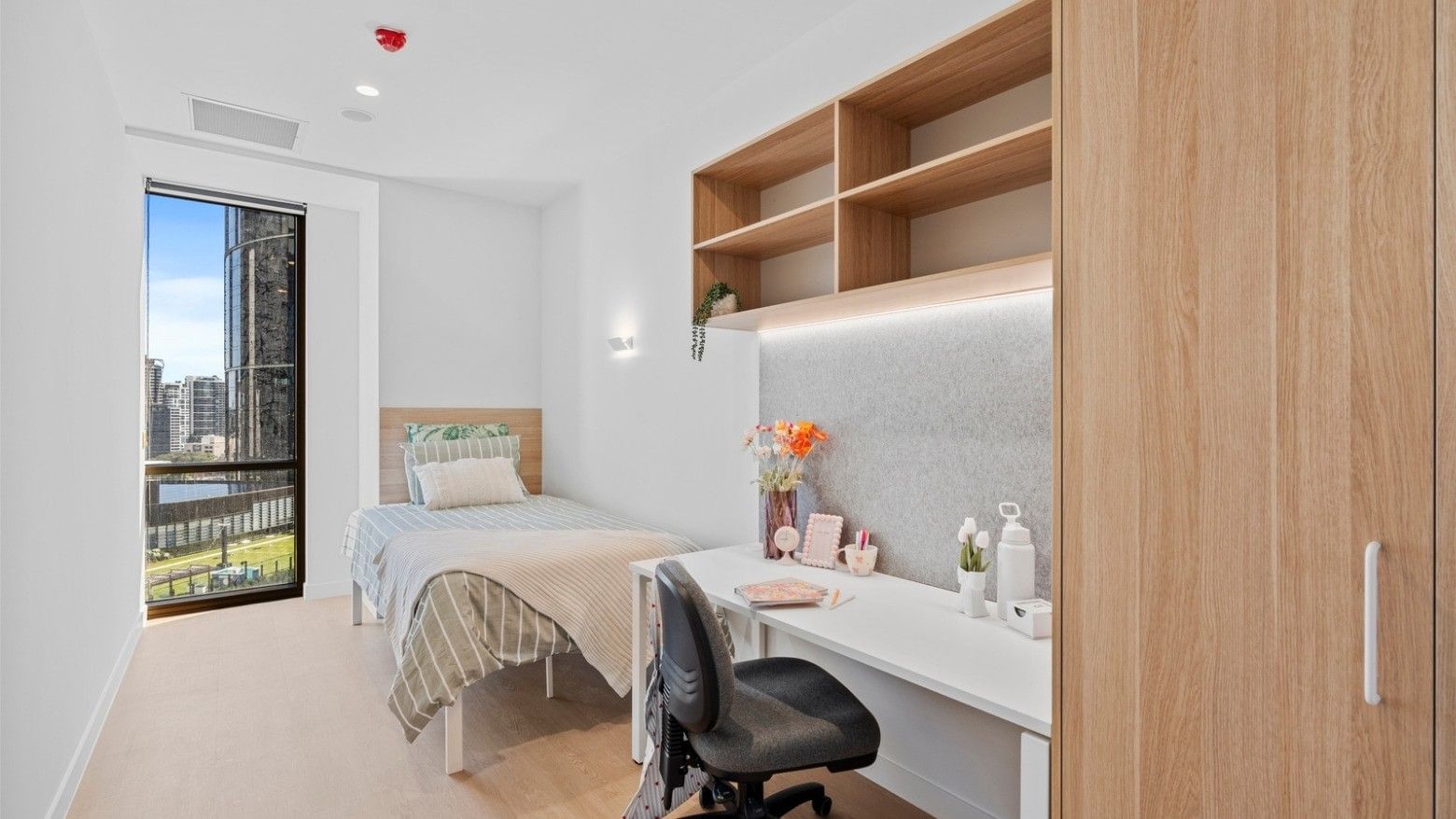Modern room with a bed, desk, chair, and balcony at UniLodge Brisbane City.