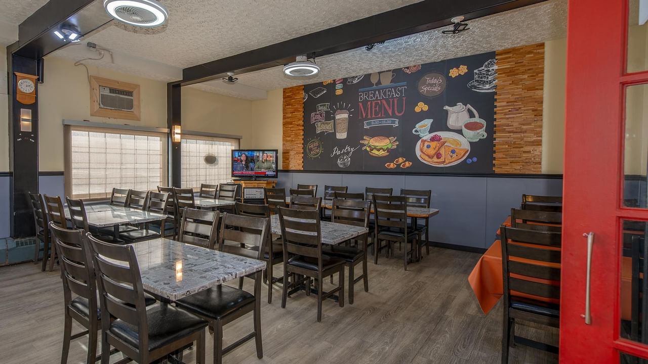 Dining area with tables and chairs with a menu on the wall.