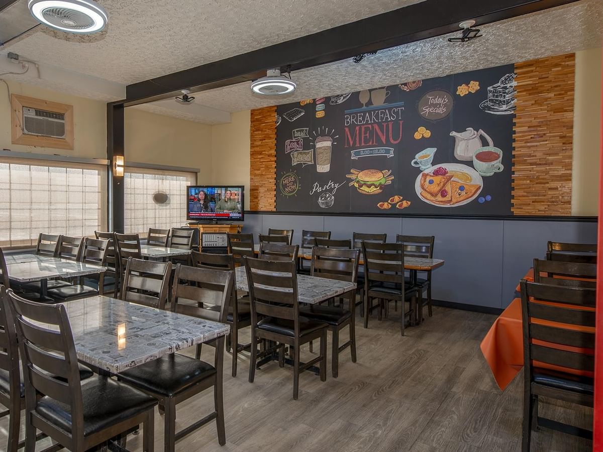 Dining area at Sam’s Friends Kitchen with breakfast menu mural.