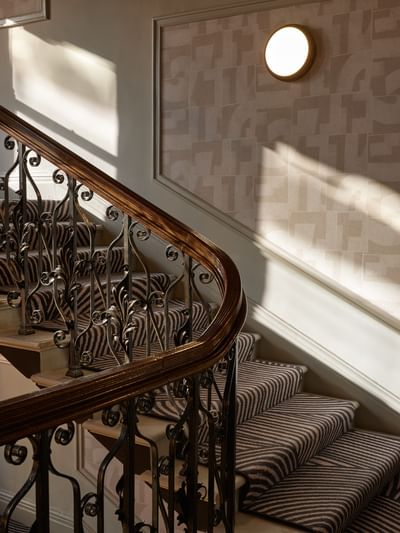 Historic staircase at The Met Hotel Leeds, England, with ornate iron railings and a dramatic striped carpet runner