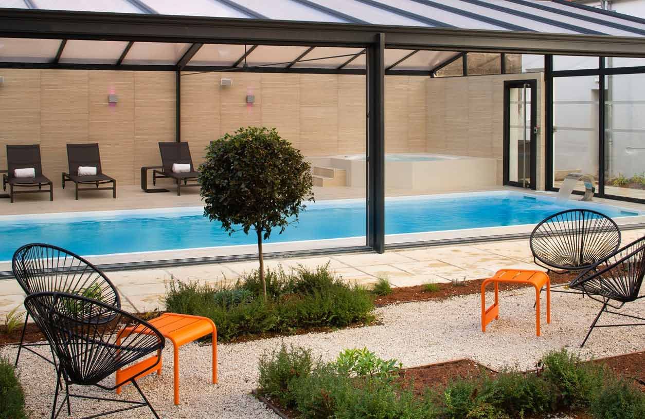 Chaises longues et bains de soleil dans la zone de la piscine couverte de l'Oceania Le Jura Dijon