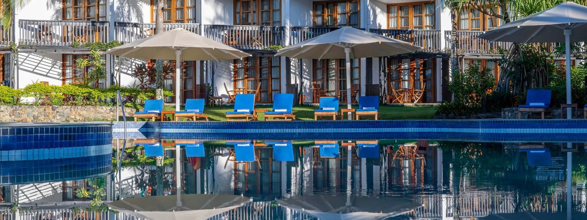 Swimming pool with lounge chairs under umbrellas at Warwick Fiji Resort and Spa in Korolevu