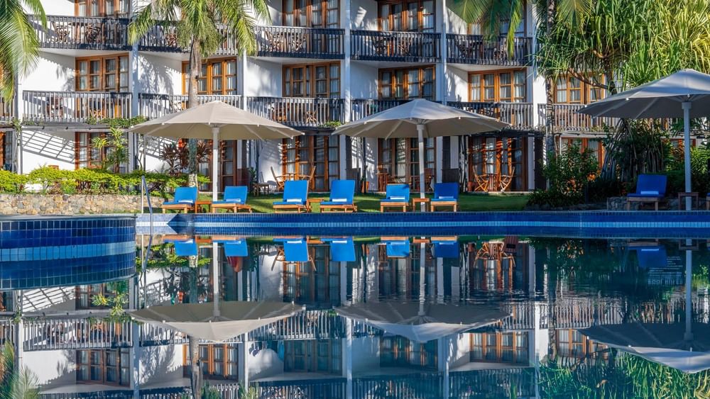 Swimming pool with lounge chairs under umbrellas at Warwick Fiji Resort and Spa in Korolevu.