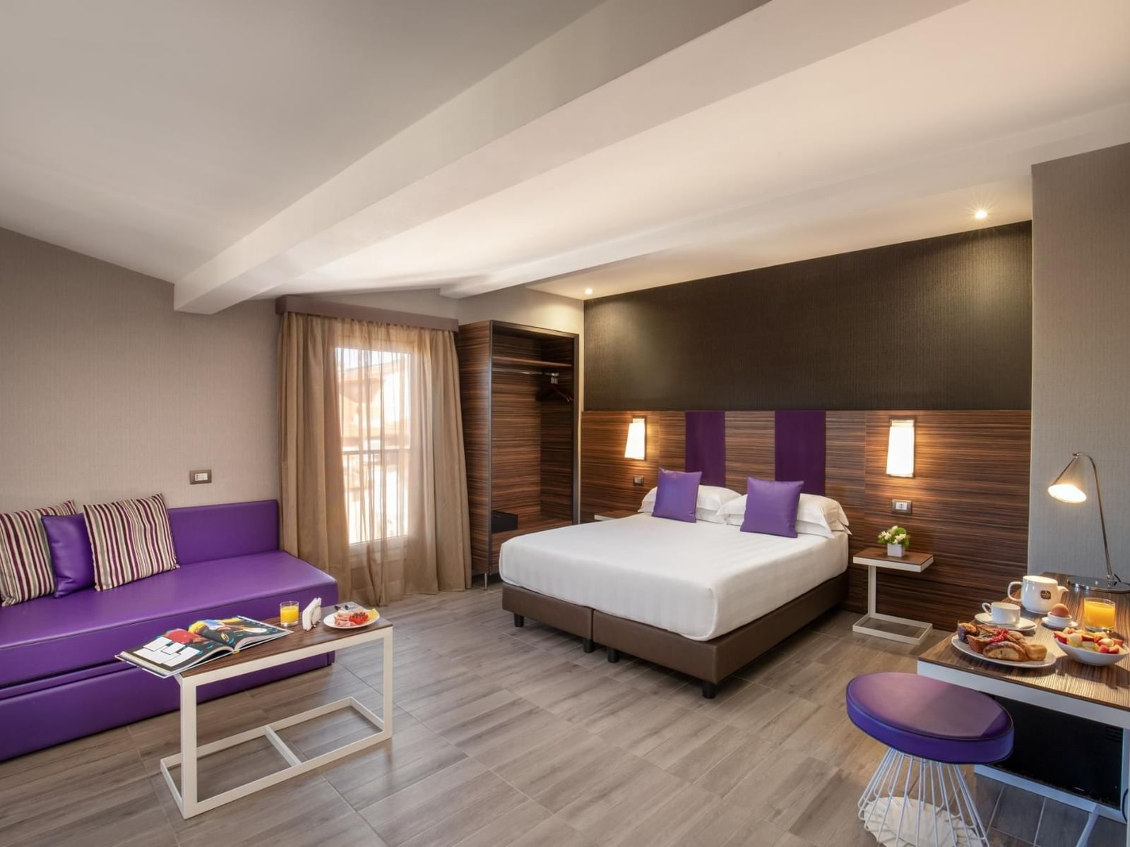 The Republic View Suite featuring a double bed, a cozy sofa, and a dining table with breakfast at The Republic Hotel