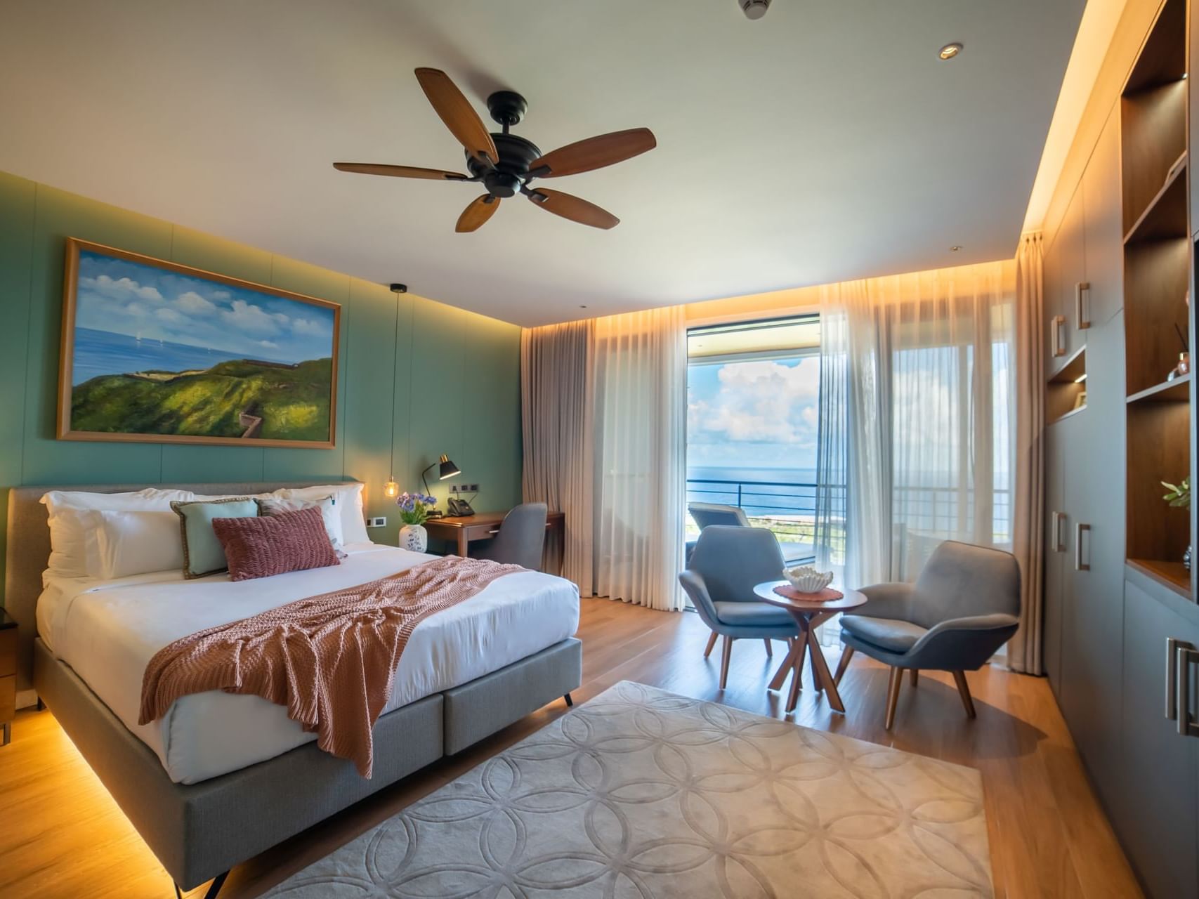 Seating area and workspace by the bed in Deluxe Ocean View Room, accented with green walls and artwork at Golden Rock Resort