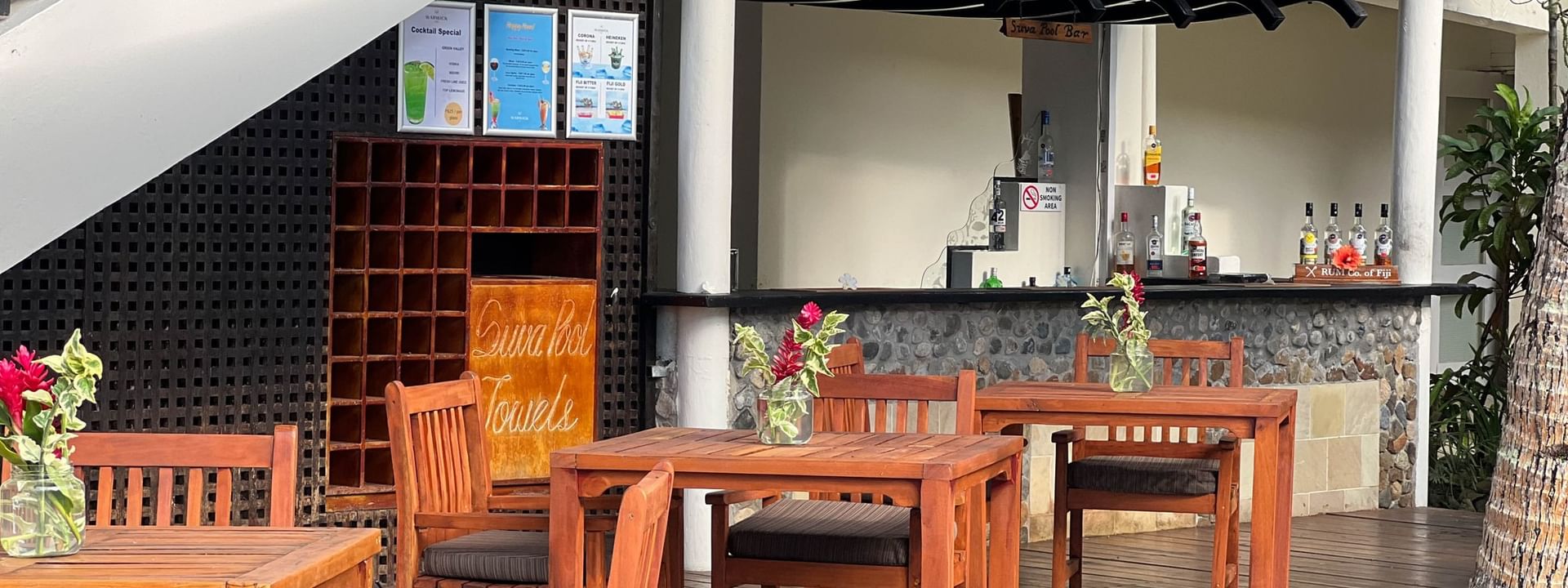 Outdoor wooden dining area with tables and chairs next to a bar at Warwick Fiji Resort and Spa, Korolevu