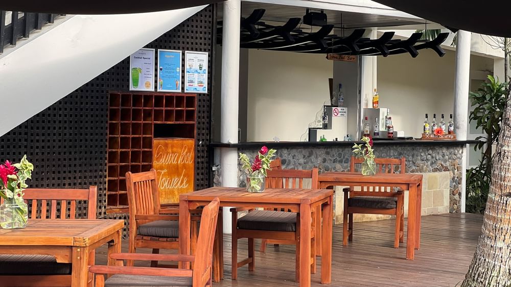 Outdoor wooden dining area with tables and chairs next to a bar at Warwick Fiji Resort and Spa, Korolevu.