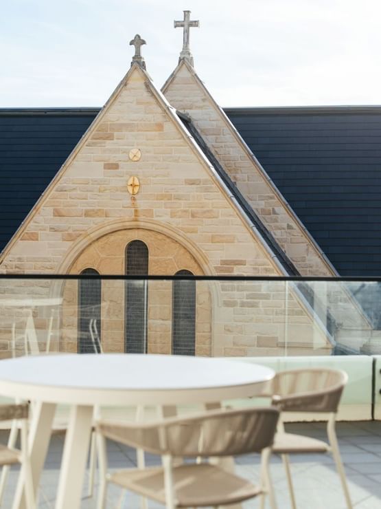 Village Terrace Twin at Elysium Manly showing a round table by a stone building facade under the sky, near the hotel area