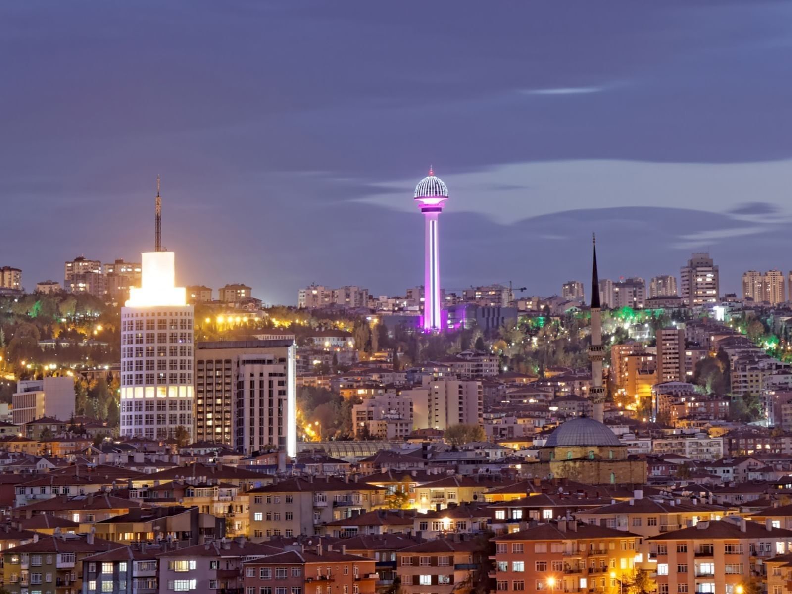 Atakule tower by city lights surrounding a mosque dome under a purple dusk sky near Warwick Ankara