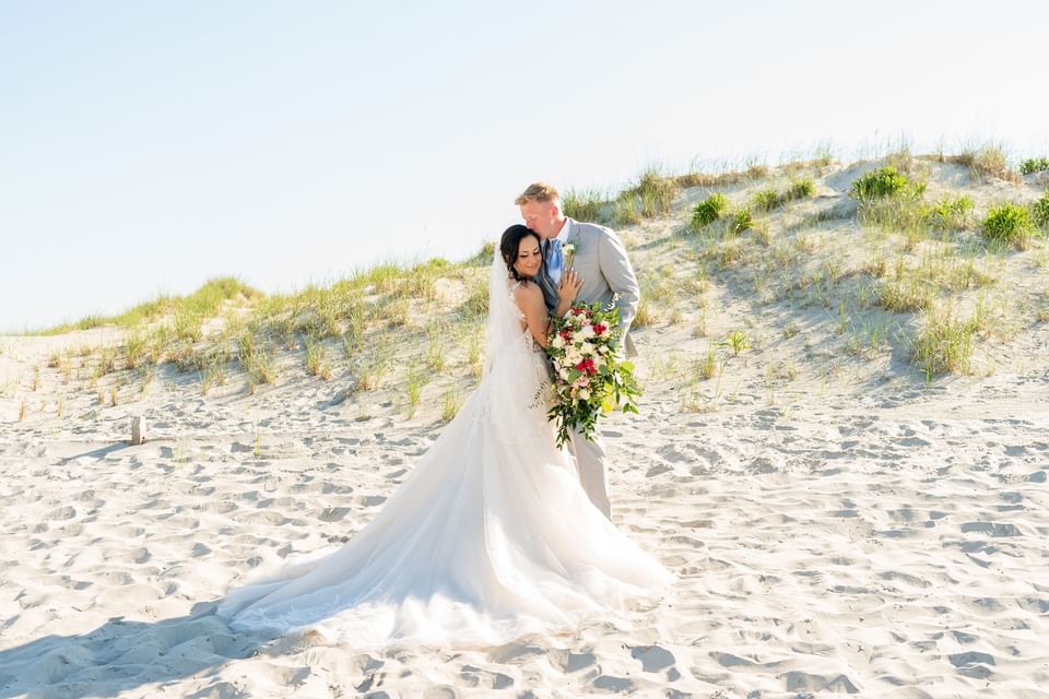 Newlyweds pose for a photo on the beach at our Avalon wedding venue
