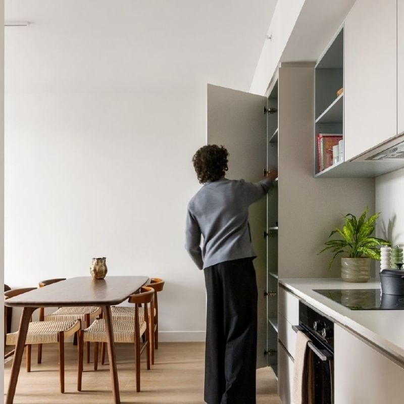 Photo of a kitchen and dining area in an apartment at Swift Walk with a university student opening pantry doors.