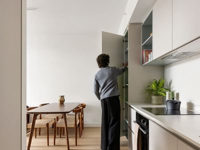 Photo of a kitchen and dining area in an apartment at Swift Walk with a university student opening pantry doors.