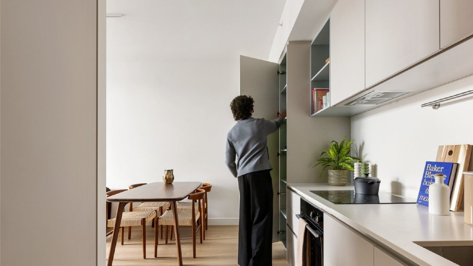 Photo of a kitchen and dining area in an apartment at Swift Walk with a university student opening pantry doors.